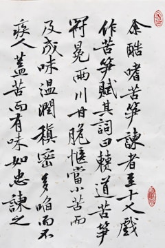 Black ink calligraphy on white paper with characters arranged vertically. There are two red stamps that serve as artistic seals, one in the top right corner and another near the bottom right.