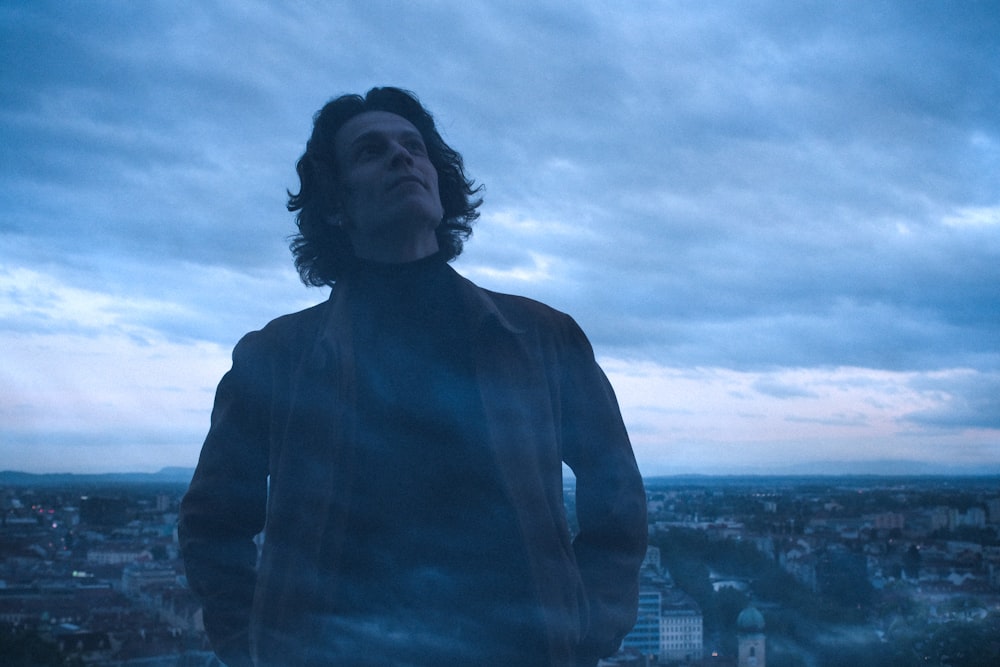 man in black leather jacket standing on top of building during daytime