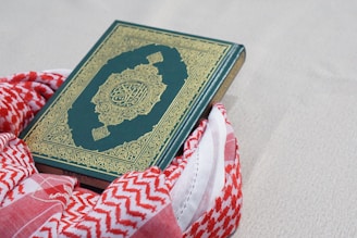green and gold book on red and white textile