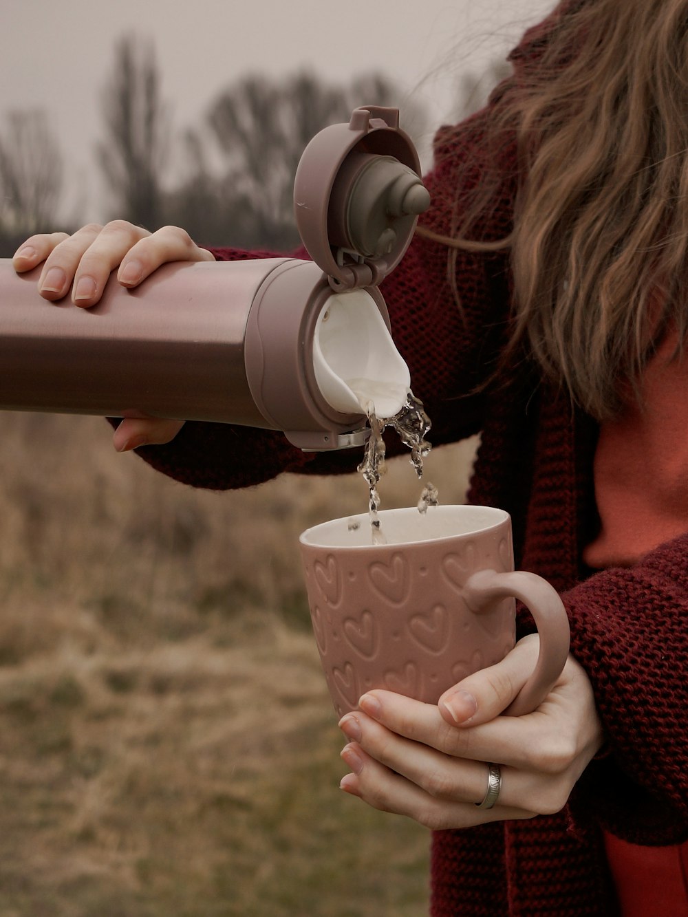 woman in red knit sweater drinking from white ceramic mug