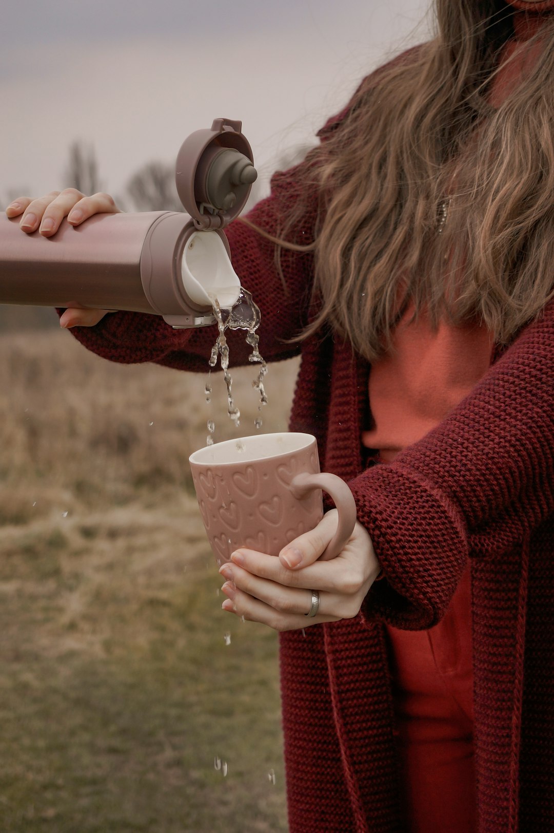 woman in red sweater holding white and brown ceramic mug