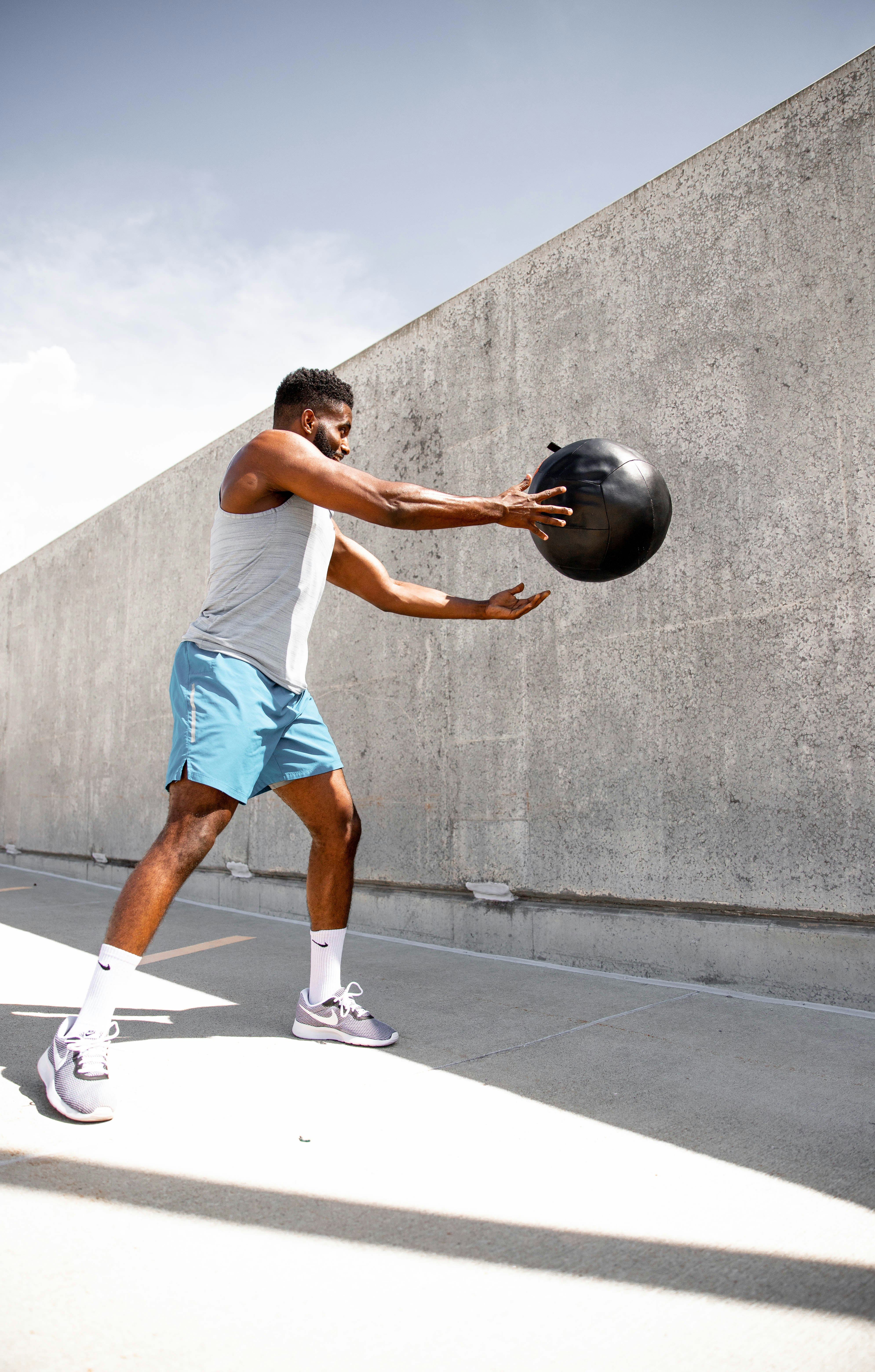 man in white tank top and white shorts holding black ball