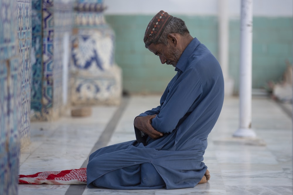 a man sitting on the ground with his hands in his pockets