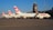 A line of Swiss airlines planes is parked on an airport tarmac. The aircraft have a distinct red and white tail design with a cross, and the word 'SWISS' is visible on the fuselage. In the background, there is an airport control tower and several lights.