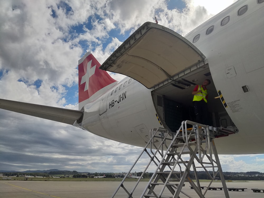 white and red airplane under white clouds during daytime