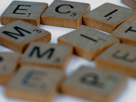 Several wooden letter tiles scattered on a surface, each containing letters and numbers typically used in word board games.