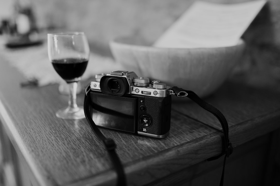 black and silver camera beside wine glass