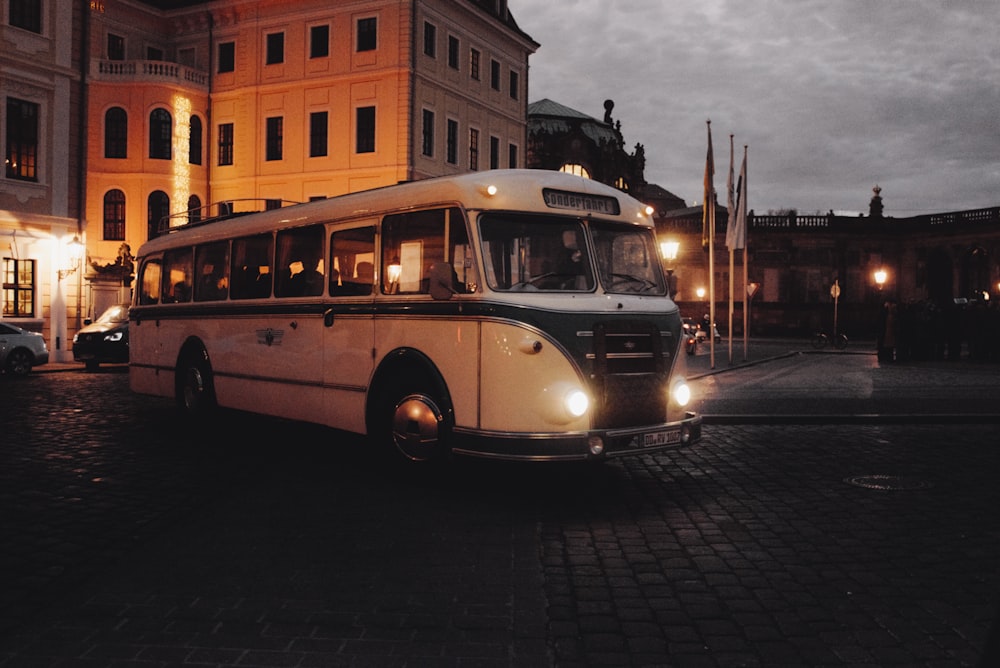 Weißer Bus tagsüber auf der Straße in der Nähe des Gebäudes