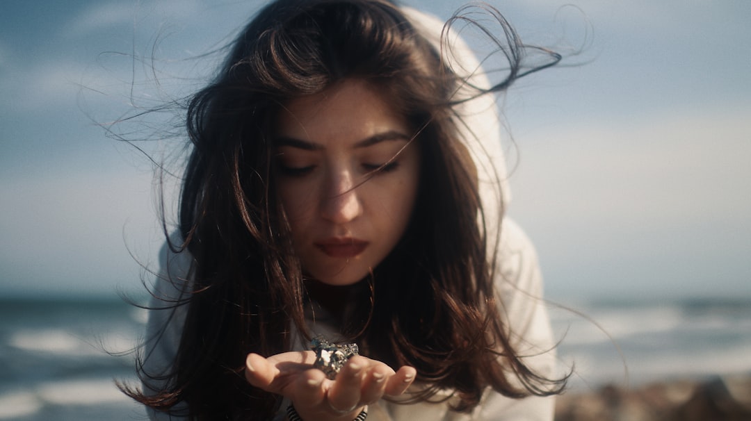 woman in white long sleeve shirt holding silver ring