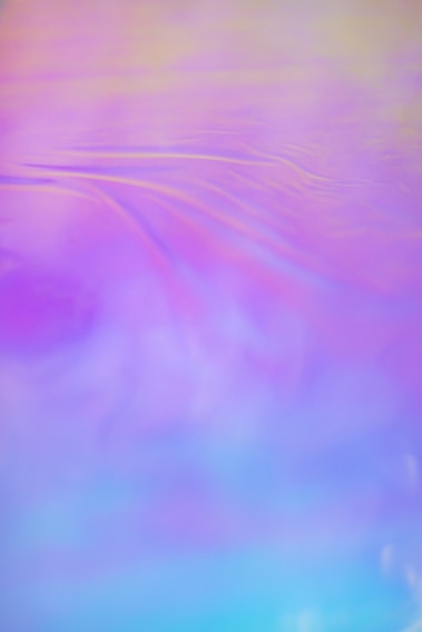 A dreamy watercolor background blending purple, lilac, and blue hues with soft playful shapes.