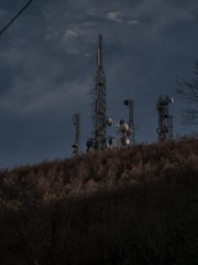 Wide shot of multiple communication towers on a hill.