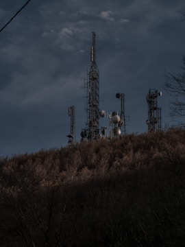 Wide shot of multiple communication towers on a hill.