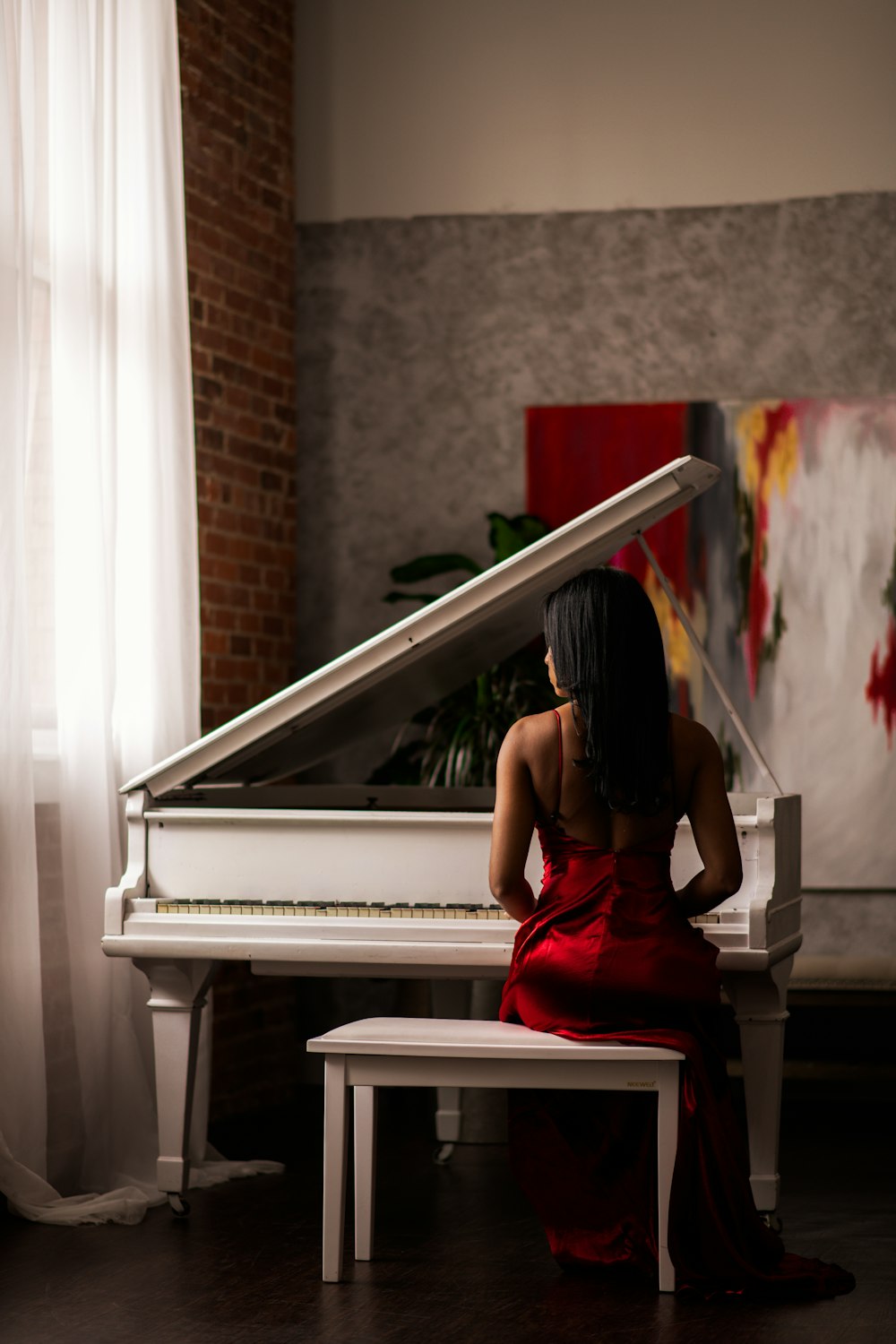 woman in red dress sitting on piano