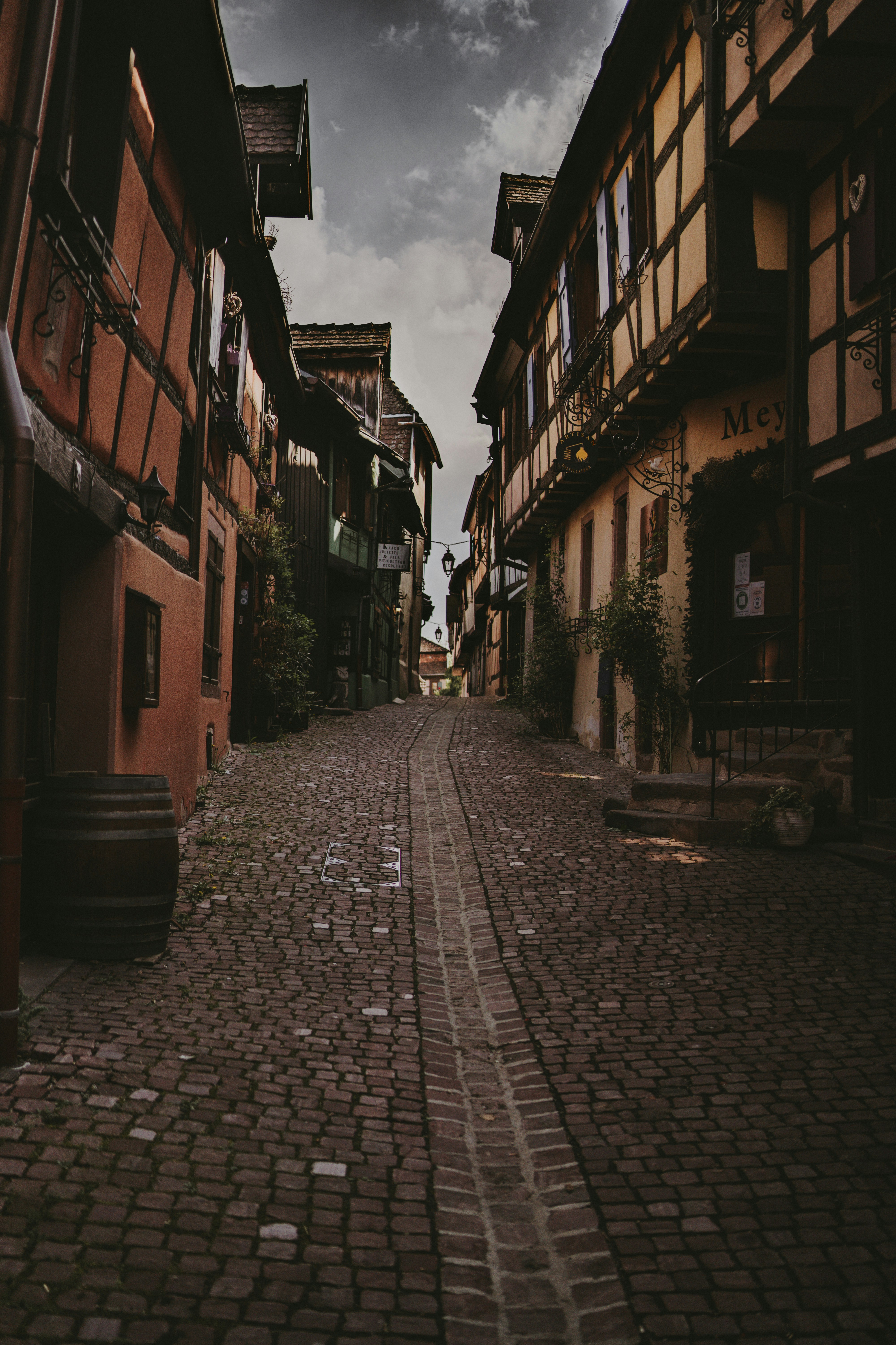 brown brick pathway between brown concrete buildings during daytime