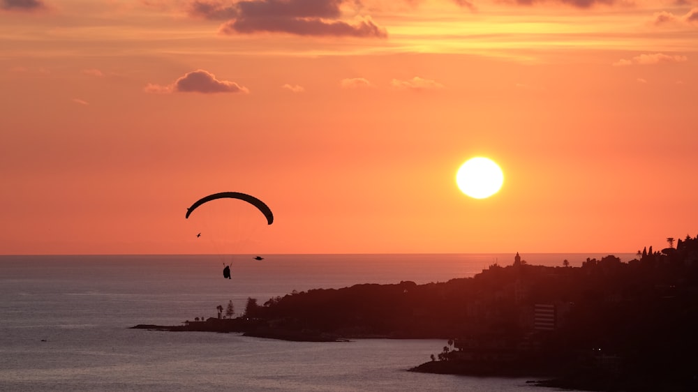 silhouette of person riding parachute during sunset