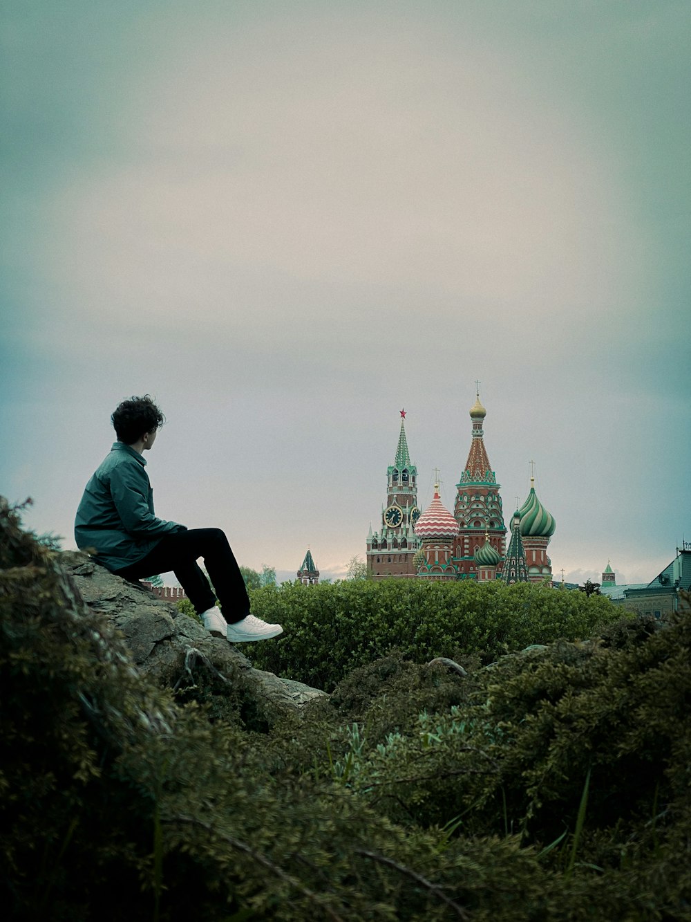 man in black jacket sitting on rock