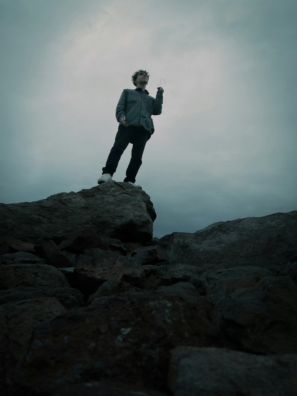 man in black jacket standing on rock formation