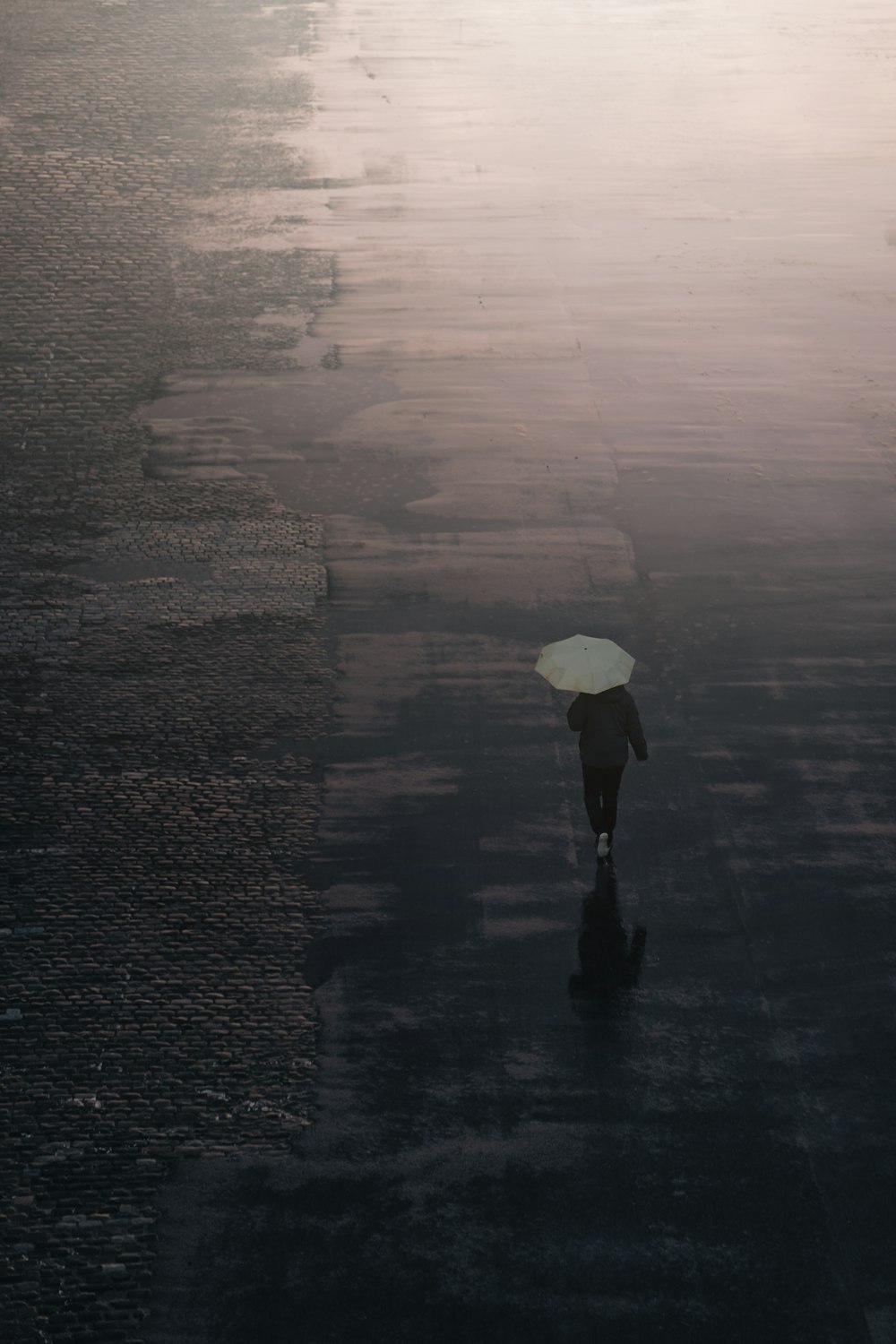 person in black jacket holding white umbrella walking on wet road during daytime