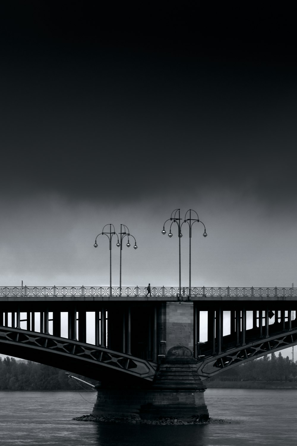 grayscale photo of bridge under cloudy sky