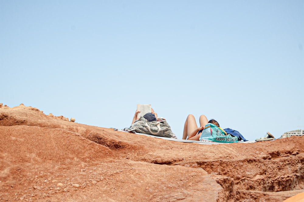 man in blue and green backpack sitting on brown rock formation during daytime