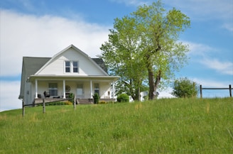 A cozy, newly built home with a welcoming front porch surrounded by green grass.