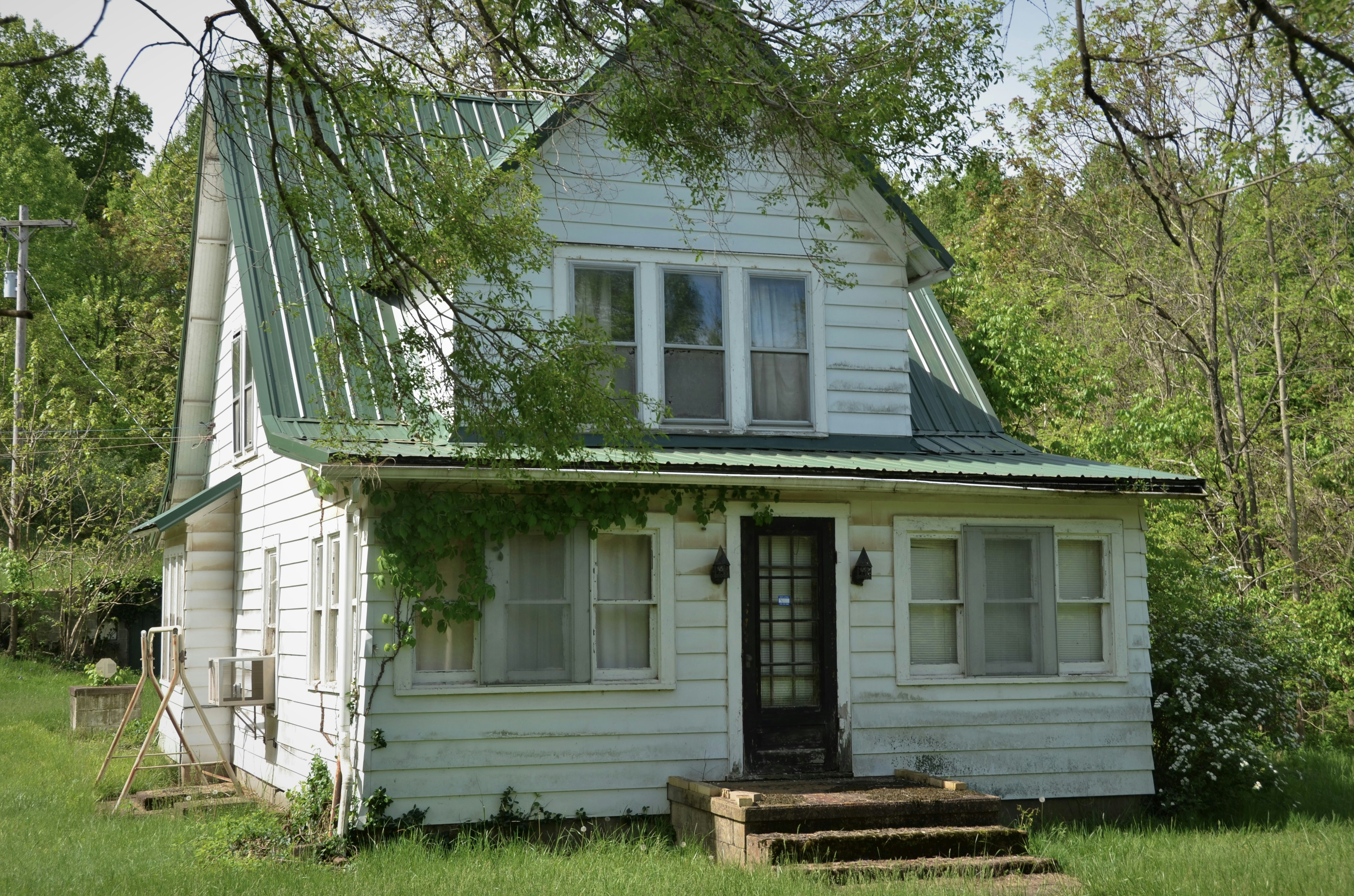 white wooden house near green tree during daytime
