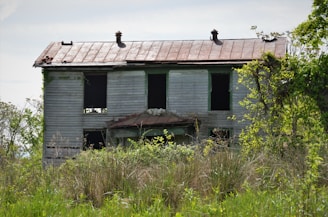 Spacious two-story house with peeling paint and overgrown yard, ideal for investors.