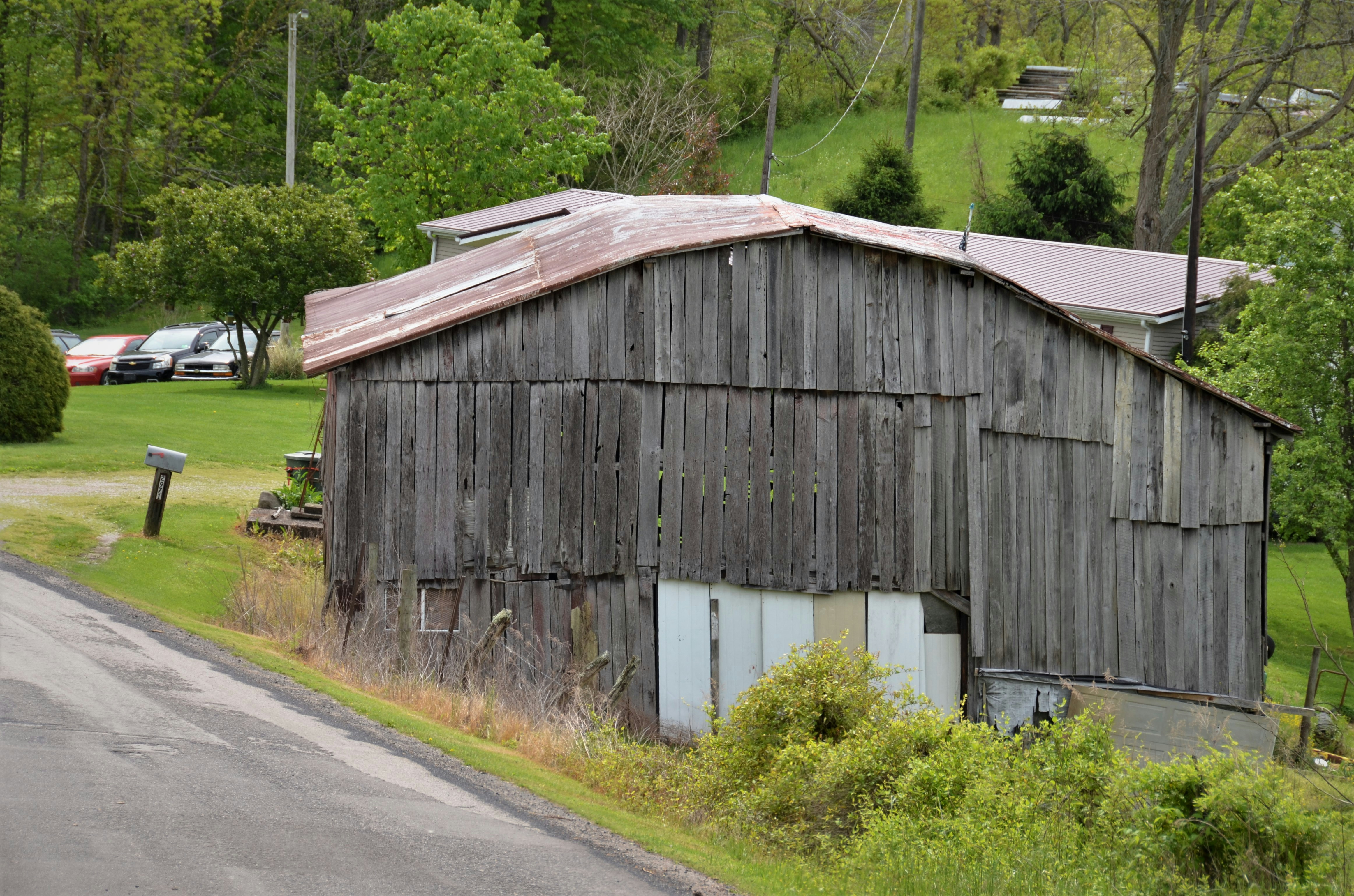 brown wooden barn near green grass field during daytime