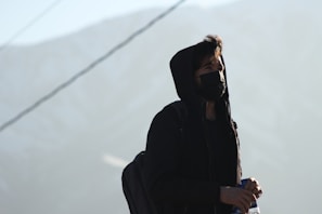 woman in black coat standing on snow covered ground during daytime