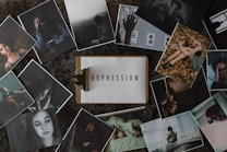 A variety of photographs surround a central image of a clipboard with the word 'Depression' typed on it. The surrounding photos depict individuals in various poses of distress or contemplation, suggesting themes of sadness, loneliness, and introspection.