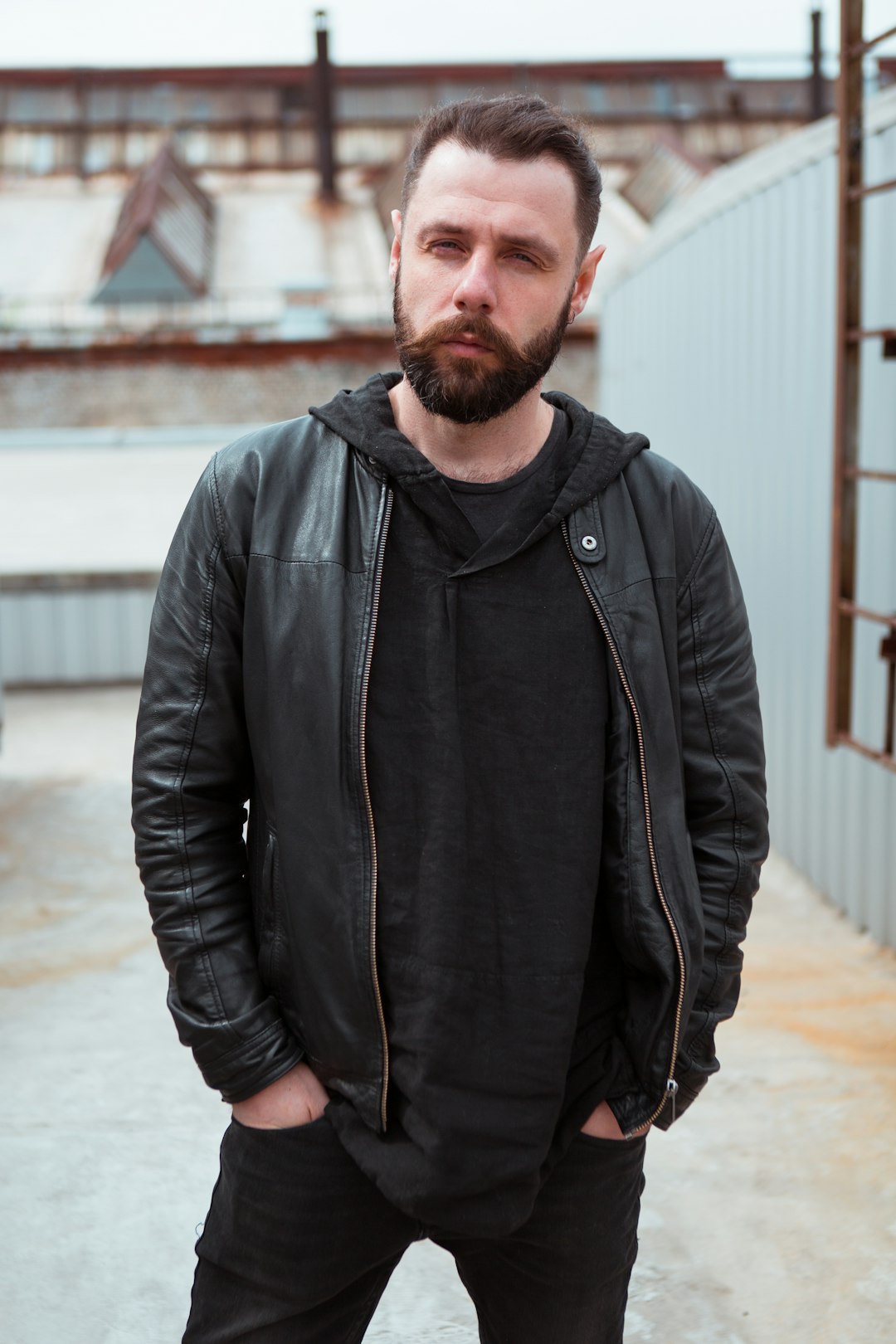 man in black zip up jacket standing on gray concrete floor during daytime