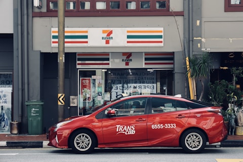 red sedan parked in front of store