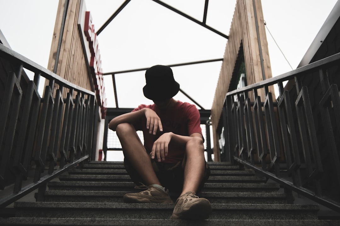 man in red t-shirt sitting on stairs