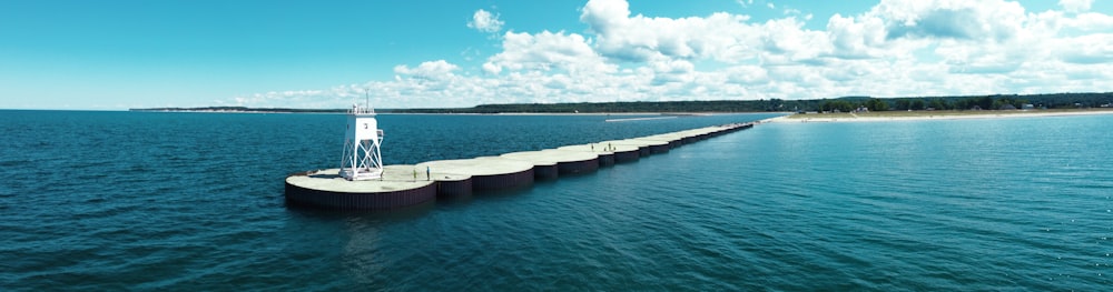 gray concrete bridge over blue sea under blue and white cloudy sky during daytime