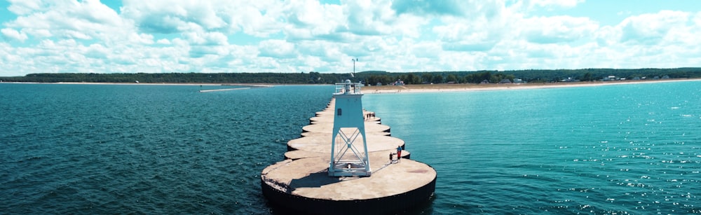 weißes und blaues Segelboot tagsüber auf dem Wasser unter weißen Wolken und blauem Himmel