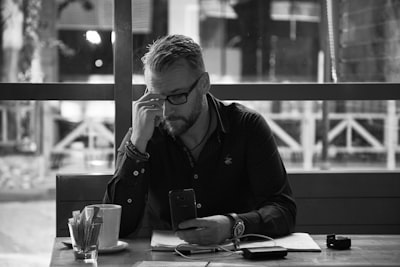 man in black jacket sitting at table difficult zoom background