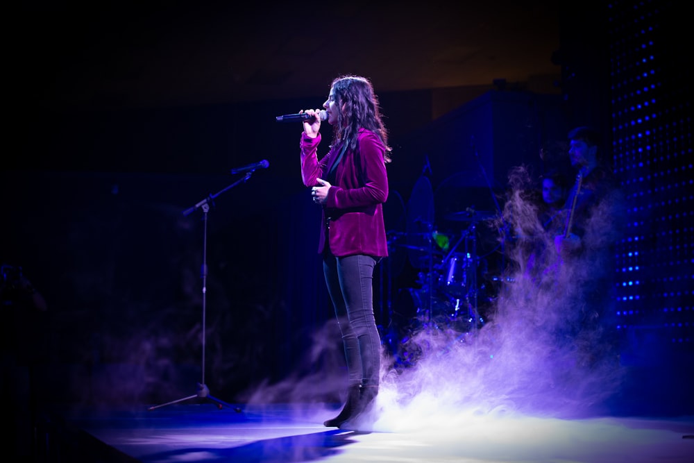 woman singing on stage with purple lights