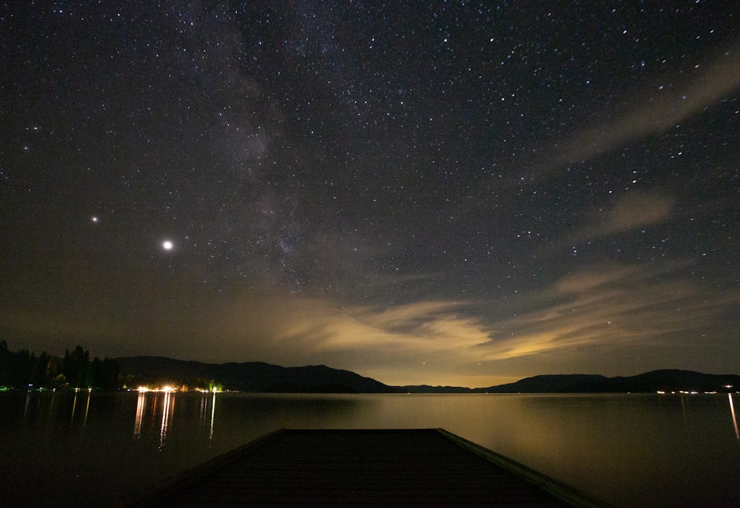 body of water near dock under starry night, Long exposure shot over Lake Pend Oreille in North Idaho with a brilliant ni