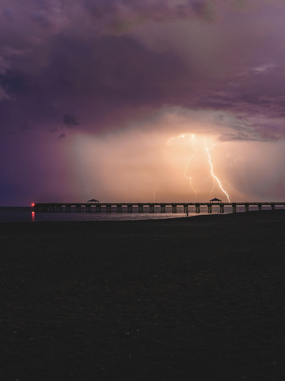 silhouette of bridge under cloudy sky during sunset