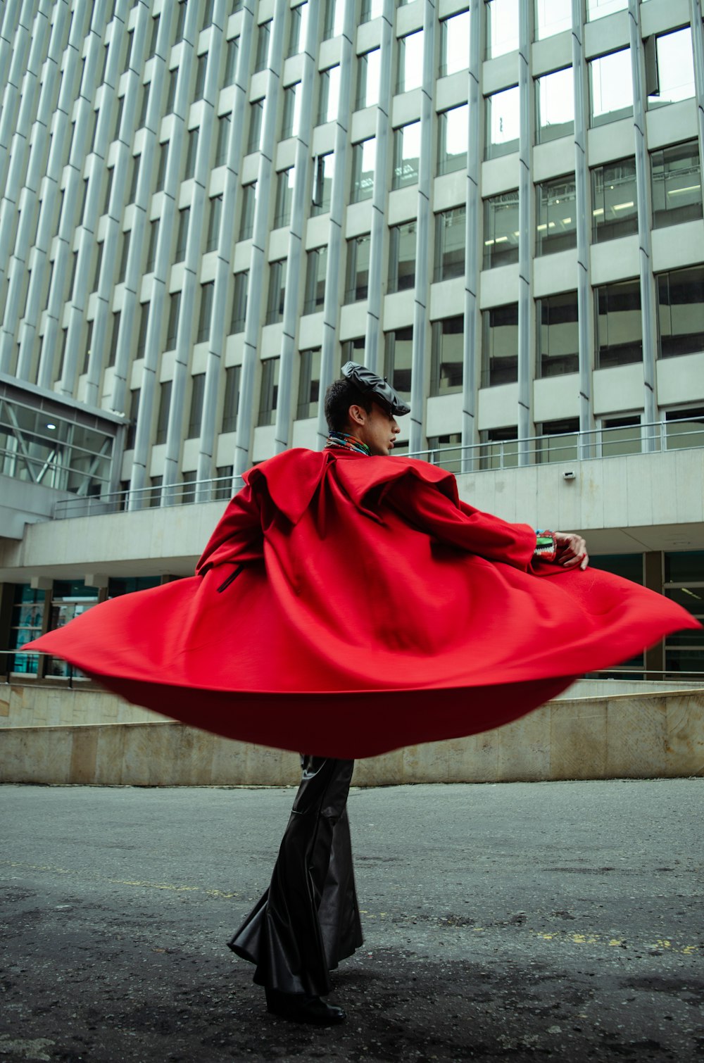 woman in red coat standing on sidewalk during daytime