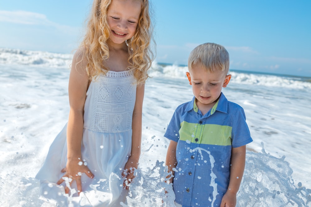 girl in white sleeveless dress standing beside boy in blue and green polo shirt during daytime