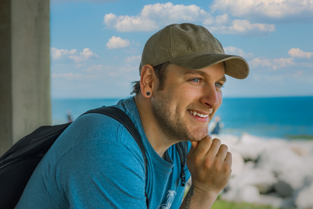 man in blue crew neck t-shirt wearing green and brown camouflage cap