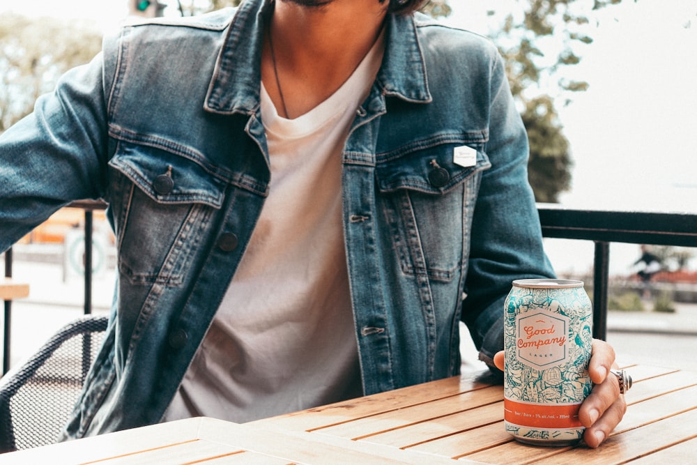 woman in blue denim jacket holding can