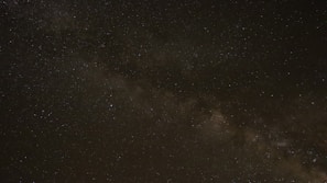 A night sky panorama showing the Milky Way galaxy stretching across the horizon