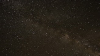 A night sky panorama showing the Milky Way galaxy stretching across the horizon
