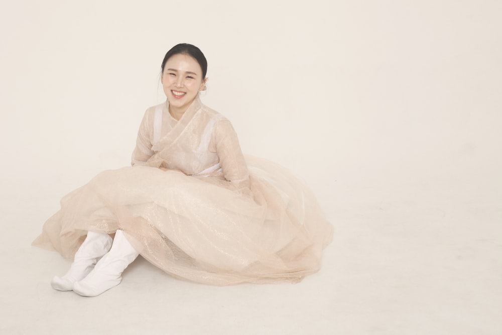 woman in white dress sitting on white floor