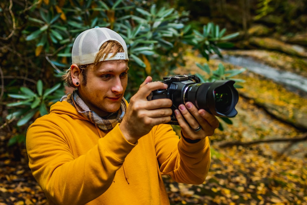 Hombre con chaqueta amarilla sosteniendo una cámara DSLR negra