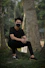 man in black crew neck t-shirt and black pants sitting on tree trunk
