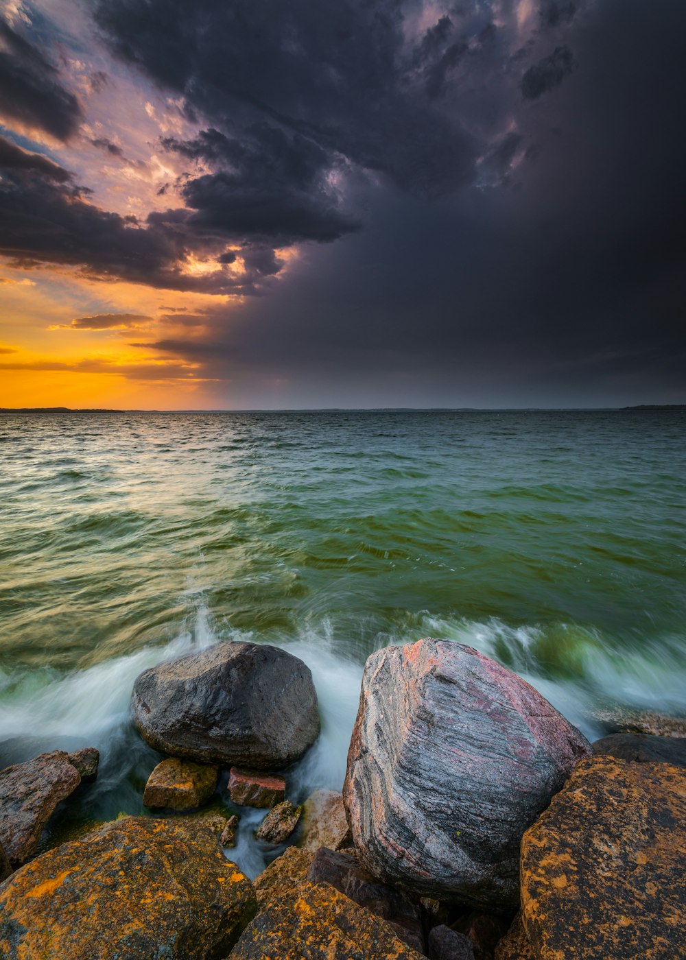 brown rocks on sea under cloudy sky during sunset