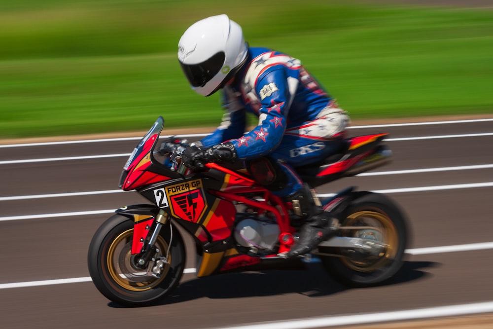 man in blue and red motorcycle suit riding on red and white sports bike